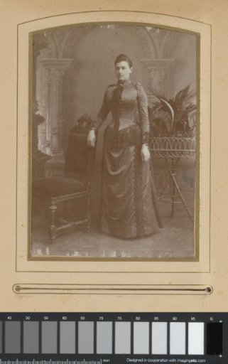 Portrait of a young woman, standing by a chair