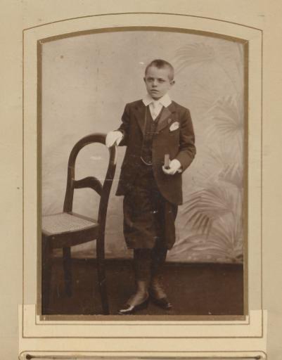 Portrait of a Boy in a Communion Suit, Standing Beside a Chair