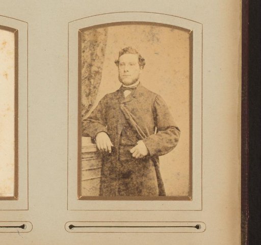 Portrait of a man in a coat, standing by a pillar