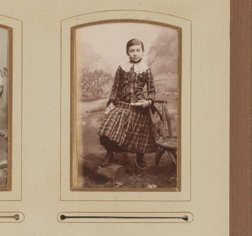 Portrait of a young woman standing by a chair with one foot on a tree trunk