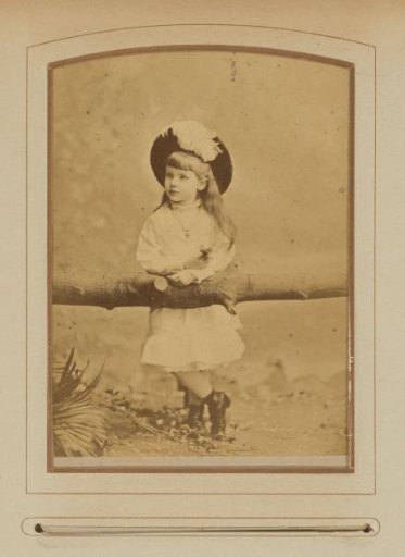 Portrait of a girl with a hat, leaning on a branch