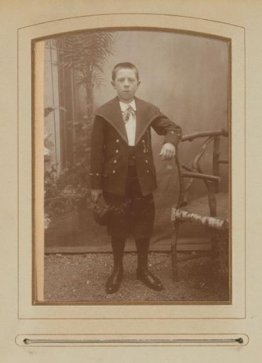 Portrait of a boy, standing by a chair
