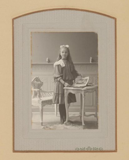 Portrait of a Girl, Standing by a Table with an Open Book