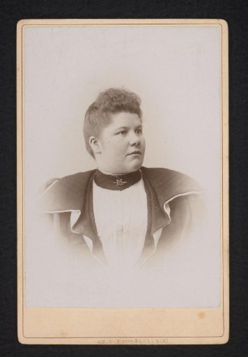 Portrait of a woman with a pin bearing the letter M