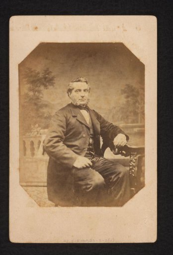 Portrait of a man with sideburns, seated at a table