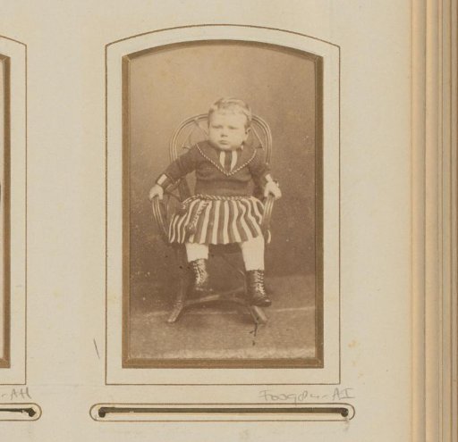Portrait of a boy, seated in a wicker chair