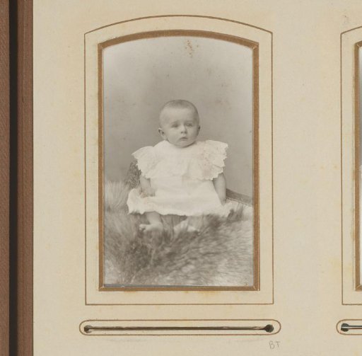 Portrait of a seated baby in a white dress