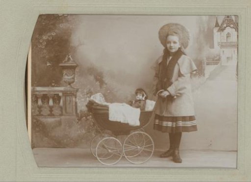 Portrait of an unknown girl with a doll's pram