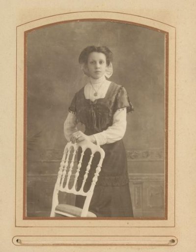 Portrait of a young woman standing by a chair