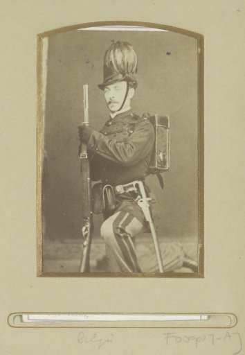Portrait of a (presumably) Belgian soldier, kneeling with a rifle and feathered hat