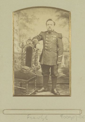 Portrait of a (presumably) German soldier, standing next to a chair