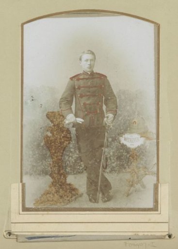 Portrait of a (presumably) Dutch military man, standing next to a helmet and a board with inscription 'until we meet again 1898'