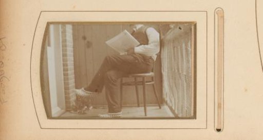Man on a chair on a balcony, with newspaper in hand