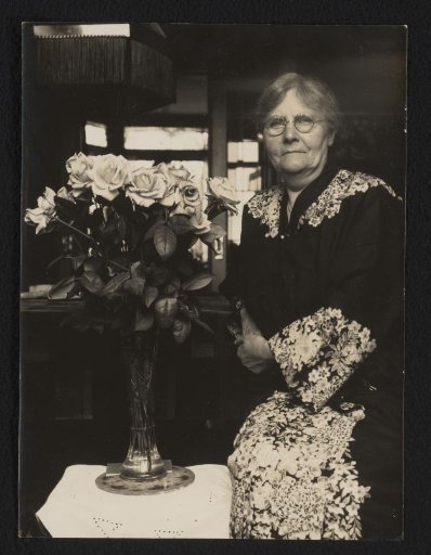 Portrait of a woman, next to a vase of roses