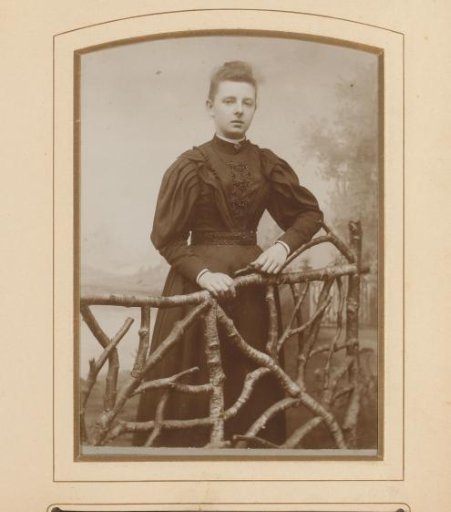 Portrait of a young woman, standing by a fence