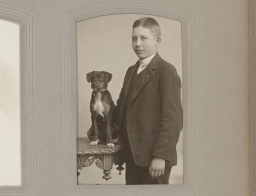 Portrait of a standing boy, next to a table with a dog