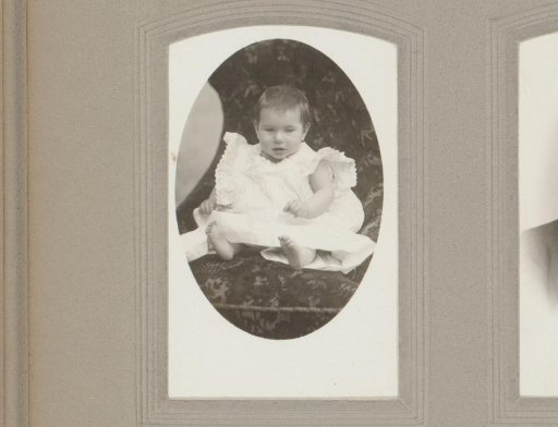 Portrait of a seated baby in a white dress