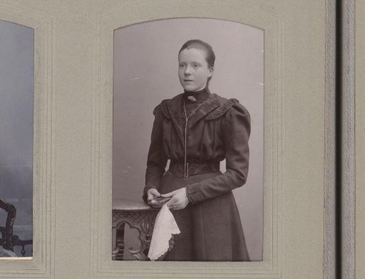 Portrait of a standing young woman with a book and white handkerchief in her hand