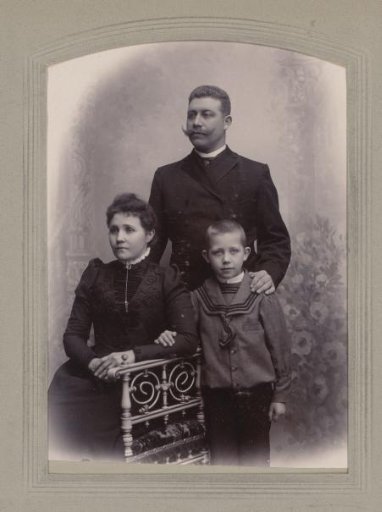 Family portrait of a standing man, a seated woman and a standing boy