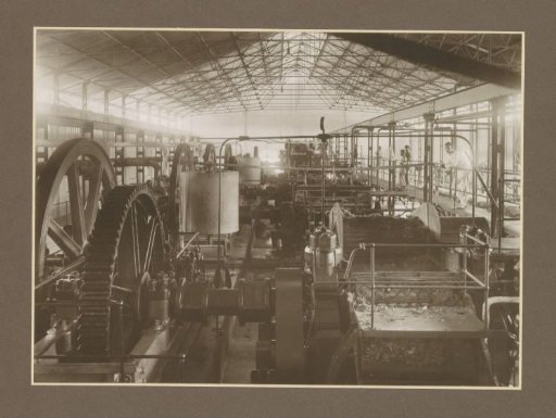 Machines and workers in a hall of the Goedo sugar factory in Djombang, Java