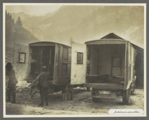 Soldiers carrying stretchers at the rear of two ambulances, presumably Italians