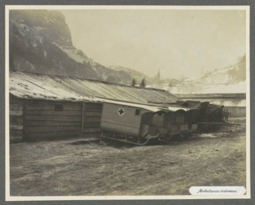 Barracks with parked ambulance sleds, one has a red cross