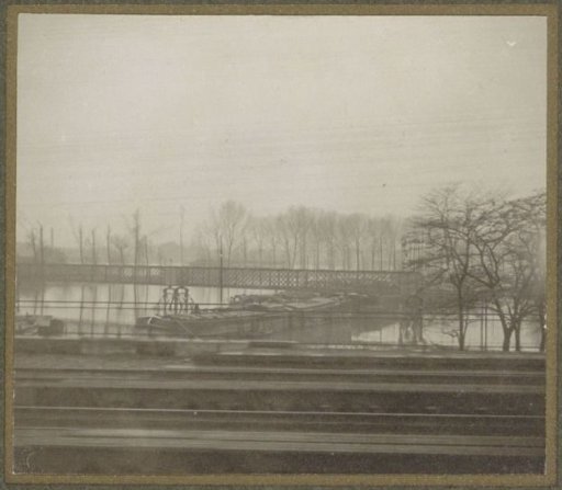 Ships under a bridge during the Paris flood, viewed from a train