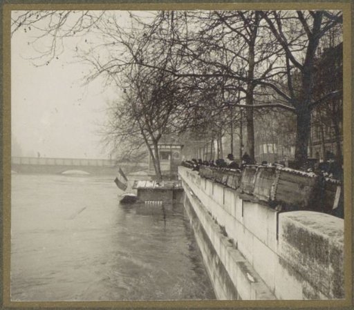 People viewing the high water level of the Seine in Paris from behind bookstalls on the quay