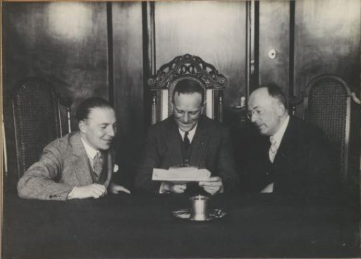Three men at a table, presumably in a director's room