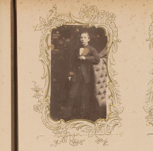 Portrait of a young man standing by a chair