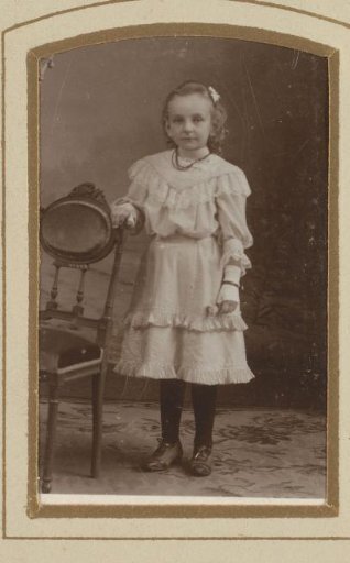 Portrait of a girl, standing by a chair
