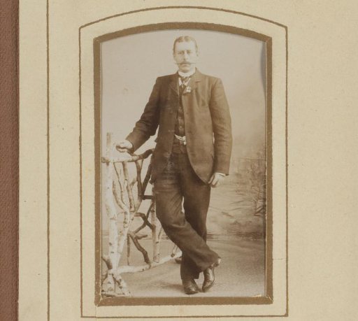 Portrait of a man with a moustache, standing by a railing