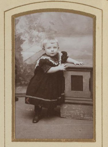 Portrait of a toddler, standing by a pillar