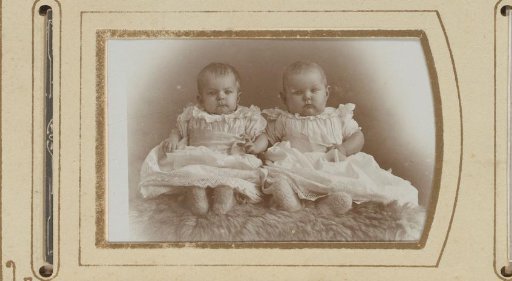 Portrait of two sitting babies in white dresses