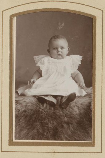 Portrait of a sitting baby in a white dress