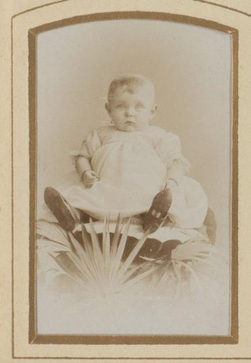 Portrait of a sitting baby in a white dress