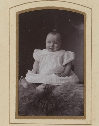 Portrait of a sitting baby in a white dress