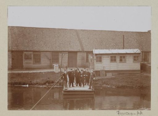 Men, presumably workers, standing on a jetty at a factory hall