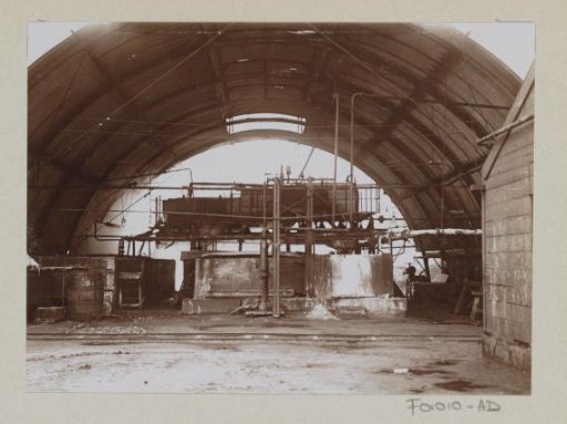 Interior of a semi-circular factory hall with a machine and pipes