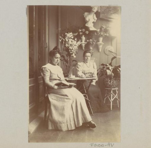 Two women, sitting in a conservatory, one reading