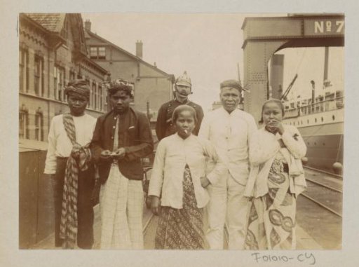 Men and women with a helmeted police officer on a quay in a harbour