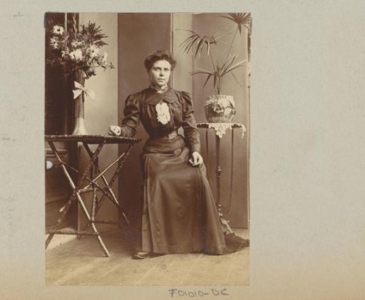 Woman seated in a conservatory at tables with flowers and plants