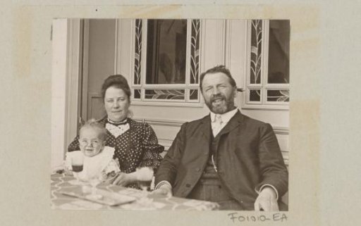 A man and a woman with a bespectacled baby at the table