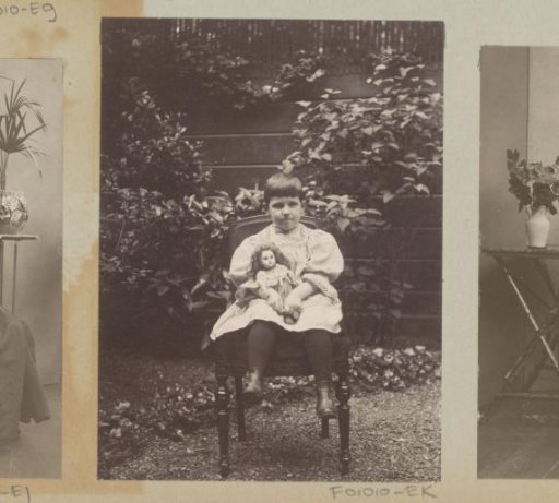 Girl seated with a doll in a garden