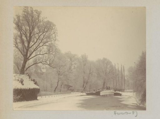Snowy landscape with bridge and trees, presumably a park
