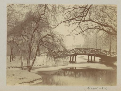 Snow-covered pond with a bridge in a park, possibly Amsterdam
