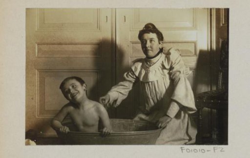 Maid bathing a child in a tub