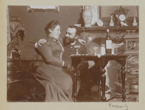 Woman with a man on her lap, glasses of wine in a living room