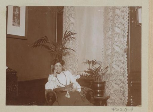 Woman with a magazine sitting in the corner of a room