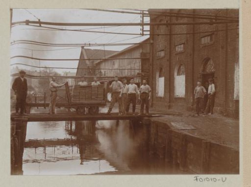 Workers busy with a loaded cart at a water trough